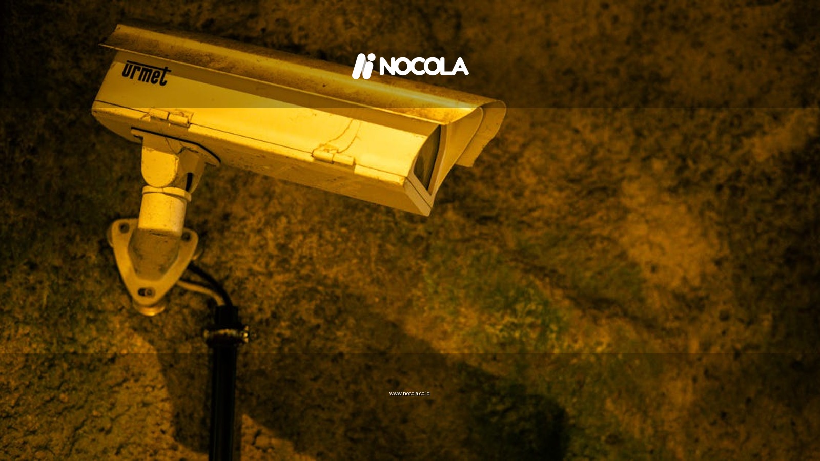 Close-up of a security camera mounted on a textured wall at night.