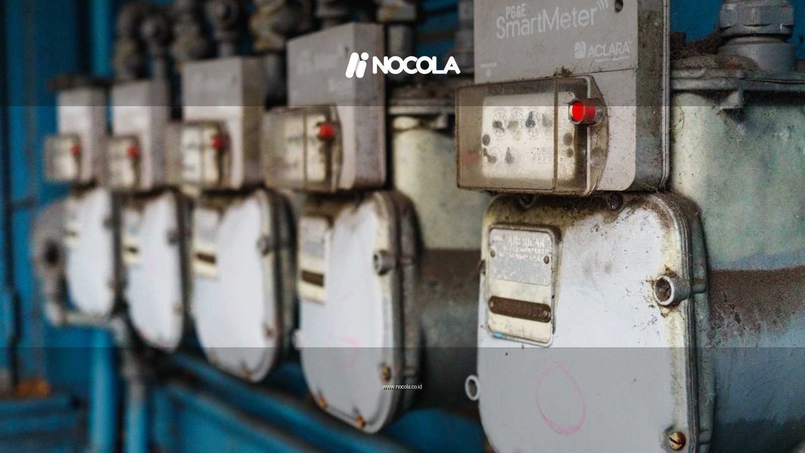 Multiple smart utility meters lined up on a blue industrial wall.
