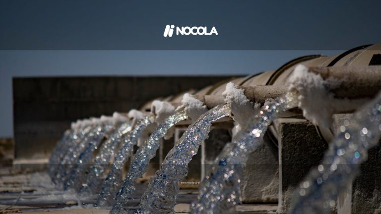 Close-up view of water flowing from industrial pipes against a clear blue sky.
